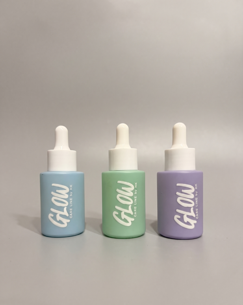 Glow Drops, sérum para cabello sin silicona en frasco gotero de vidrio azul sobre fondo gris