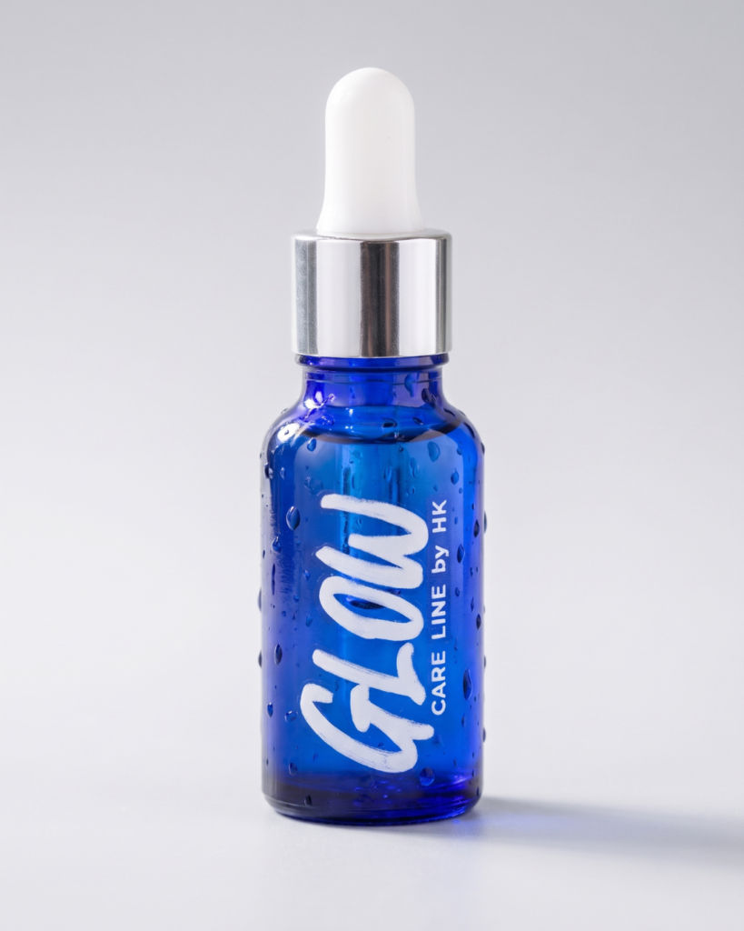 Glow Drops, sérum para cabello sin silicona en frasco gotero de vidrio azul sobre fondo gris